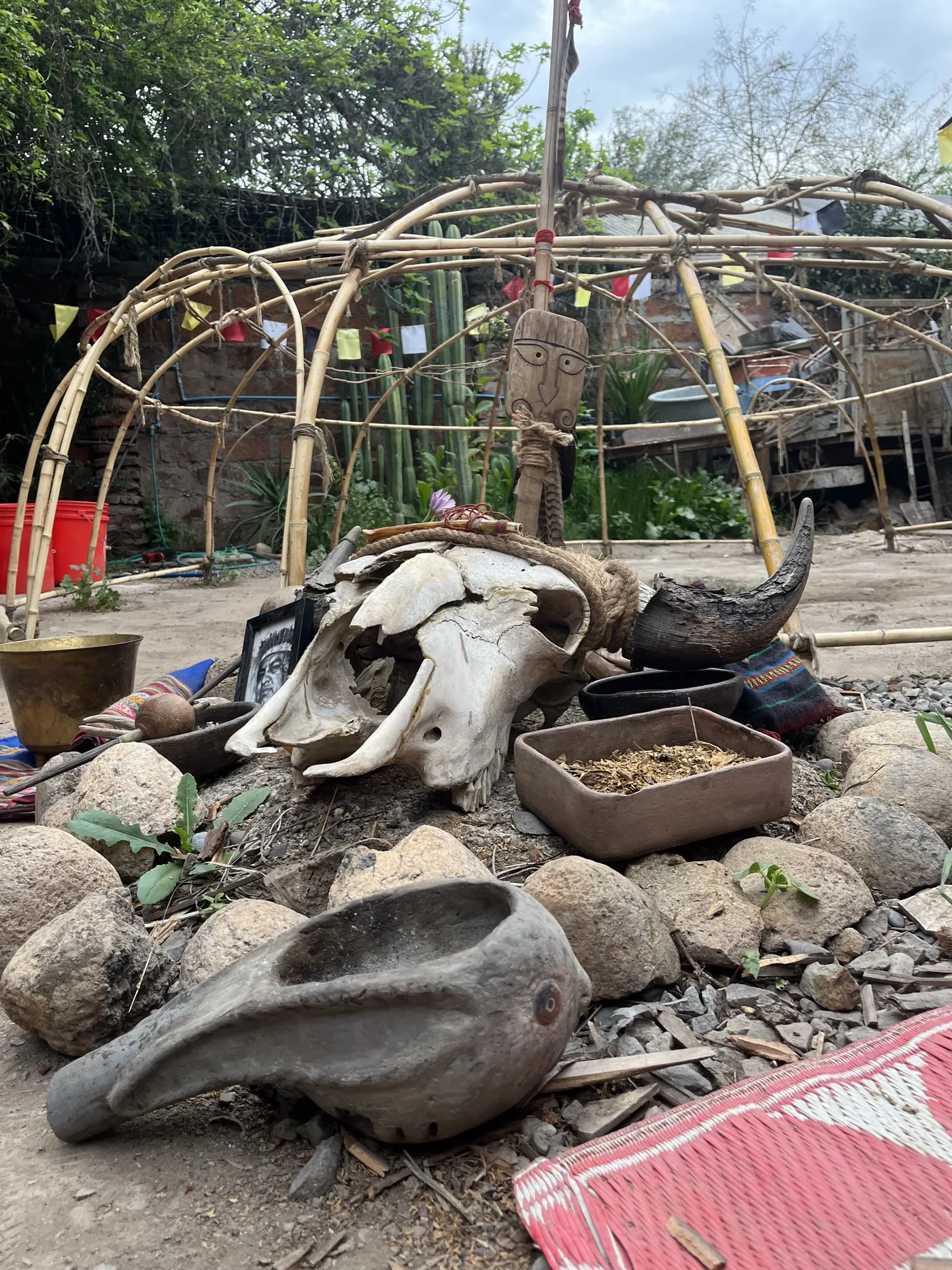 Altar del temazcal con cráneo, cuencos y piedras frente al domo